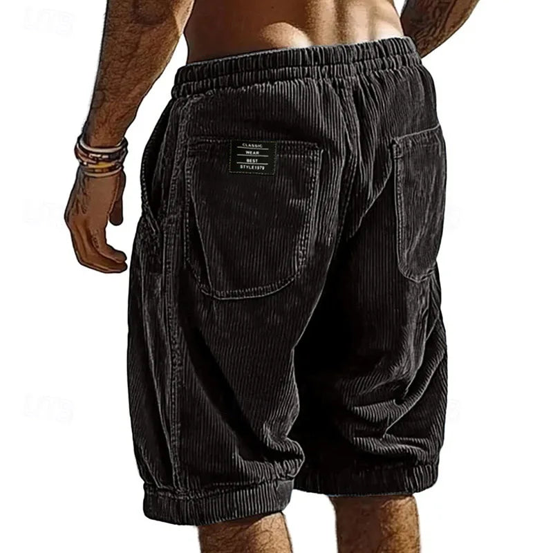 Black corduroy shorts worn by a person on a white background