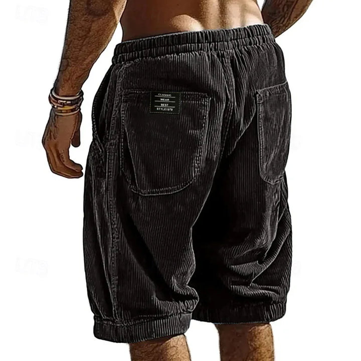 Black corduroy shorts worn by a person on a white background