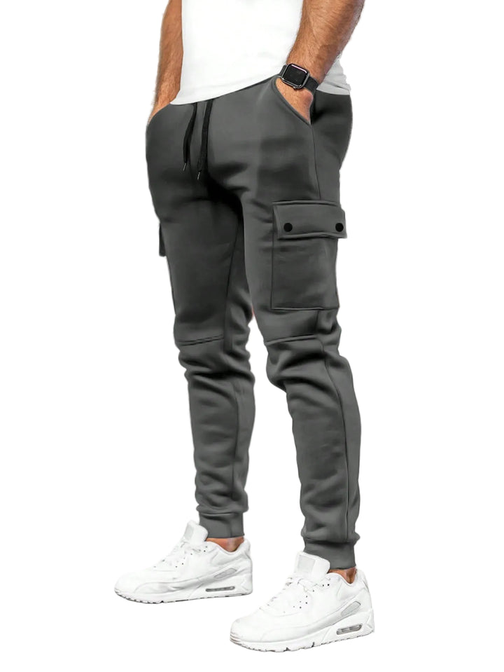 Person wearing gray cargo jogger pants and white sneakers in a white background.