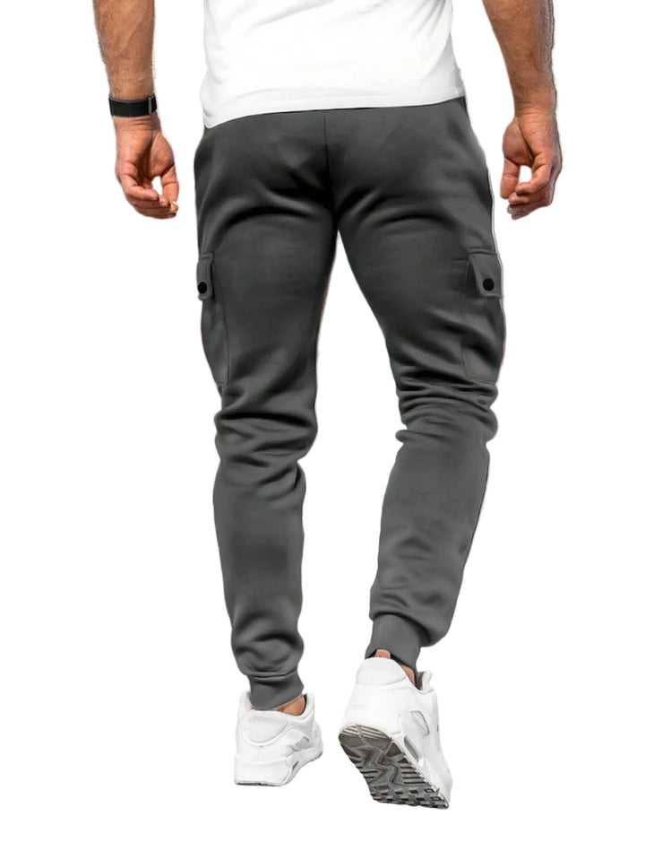Person wearing gray jogger pants and white sneakers in a white background.