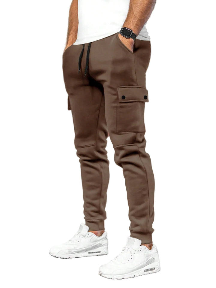 Person wearing brown cargo jogger pants and white sneakers in a white background.