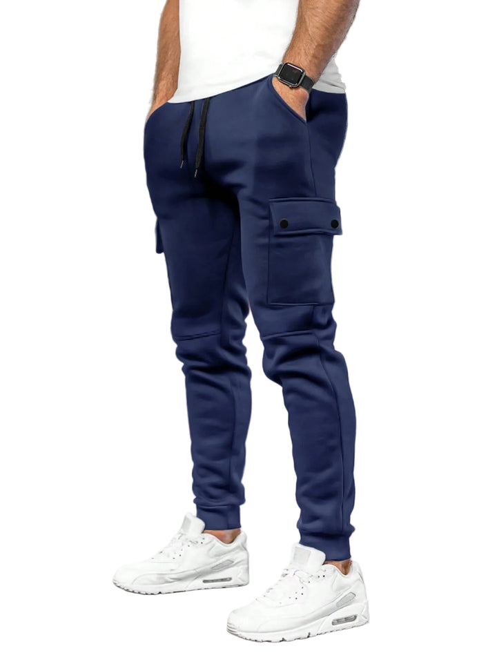 Person wearing navy cargo jogger pants and white sneakers in a white background.