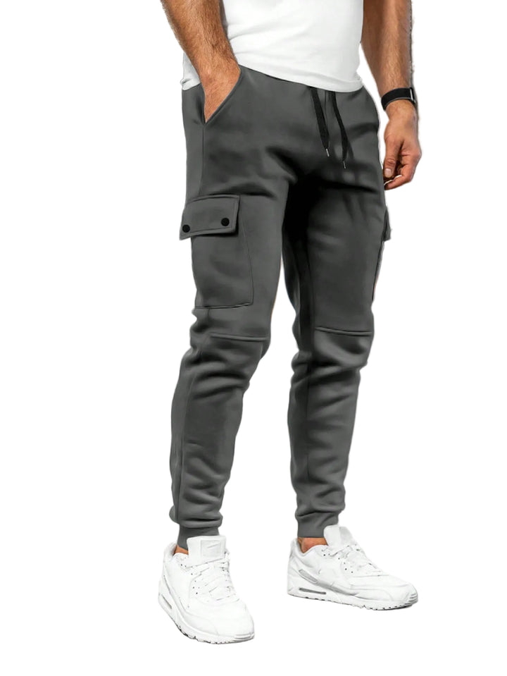 Person wearing gray jogger pants and white sneakers in a white background.