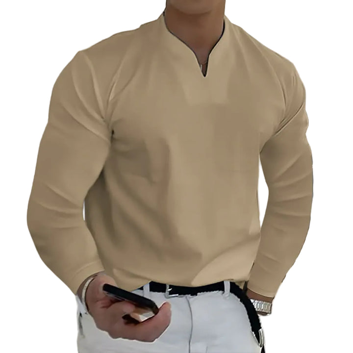 Person wearing a beige long-sleeve shirt and white pants, holding a phone.