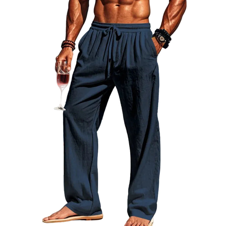 Man in navy pants holding a glass of red wine with white background