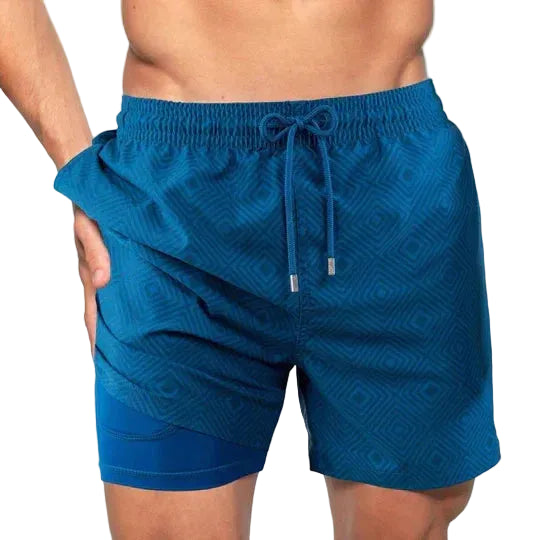 Blue patterned swim shorts worn by a person on a white background.