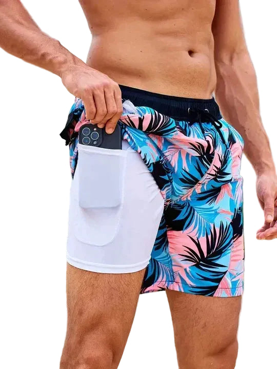 Person wearing colorful tropical print swim shorts on a white background