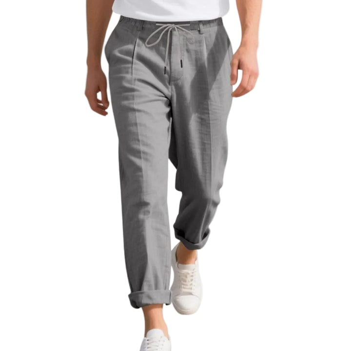 Person wearing gray pants and white sneakers on a white background