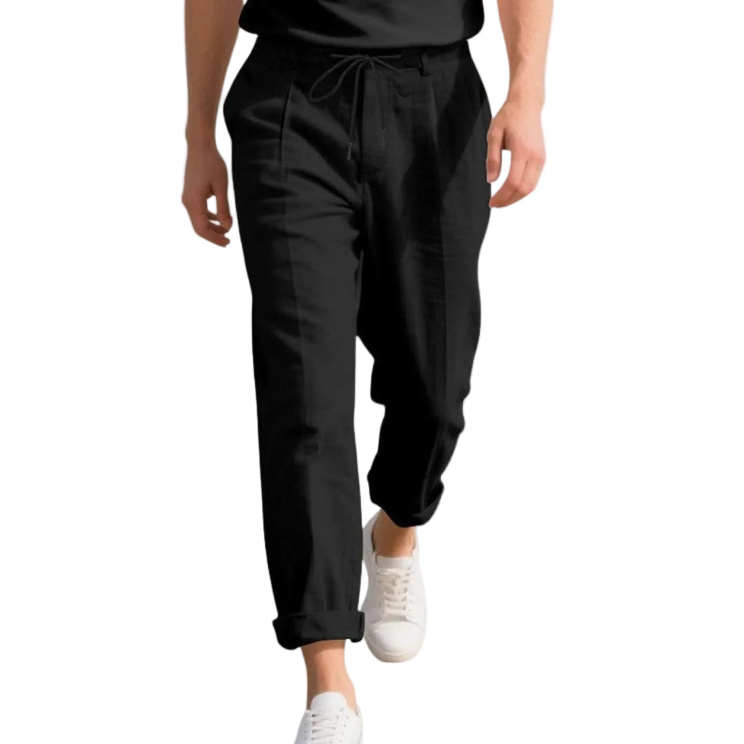Person wearing black pants and white sneakers on a white background