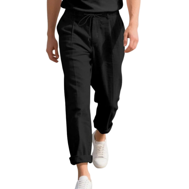 Person wearing black pants and white sneakers on a white background