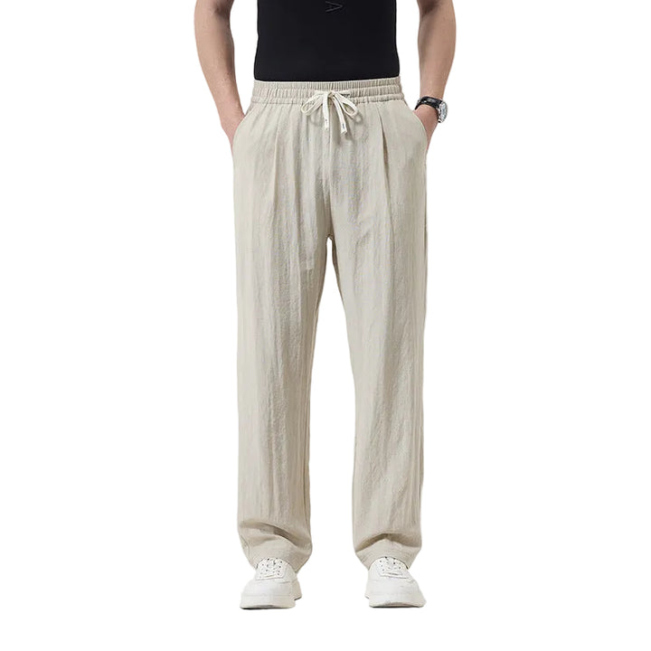 Person wearing beige pants and white shoes on a plain background